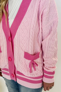 monochrome pink varsity style letterman cardigan with button front and pockets with bows on them