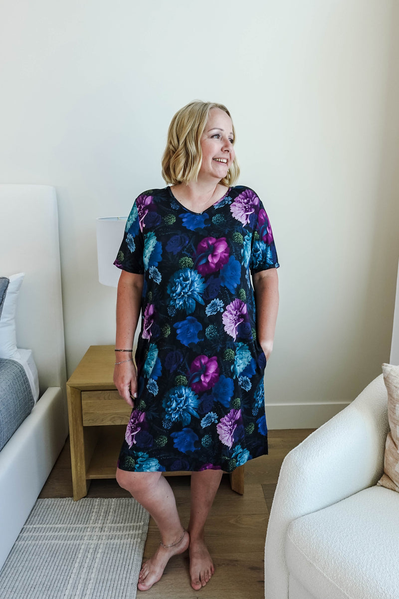 woman standing in a vneck nightgown in a moody navy floral colour