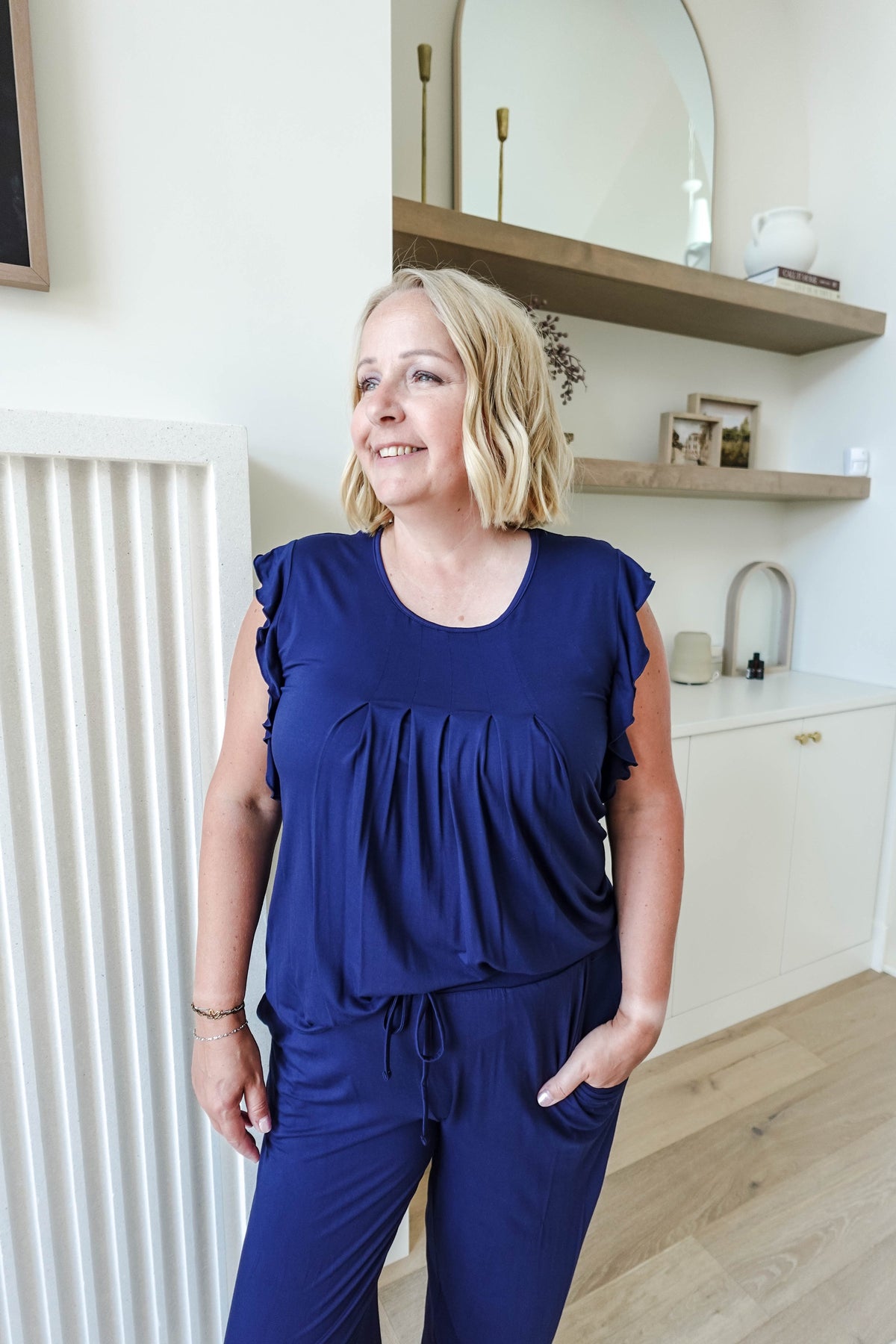 blonde woman wearing dark navy blue pajama set with flattering top and jogger pant with drawstring and pockets close up 